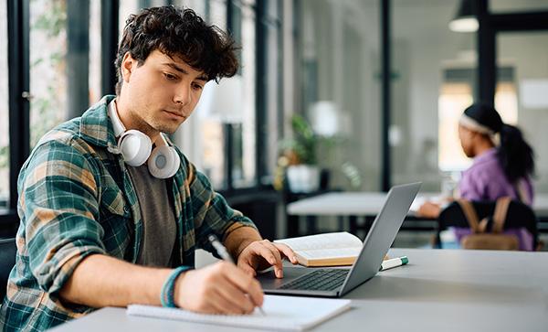 Male college student is writing down registration key dates in a notebook